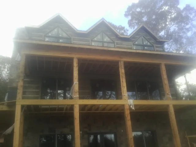 Dormers and porch framing on a large log home under construction — Roof Coating work by our crew in Big Bend